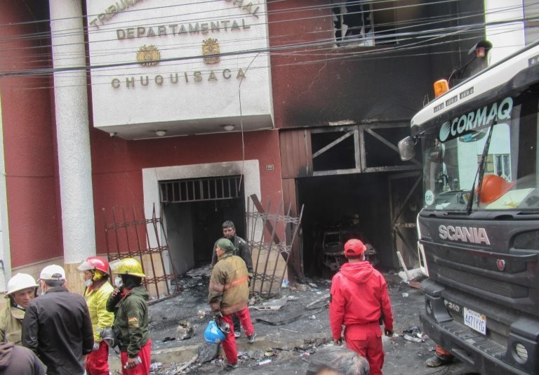 Пожарные работают возле избирательного участка Боливии, подожженного протестующими 21 октября 2019 года.