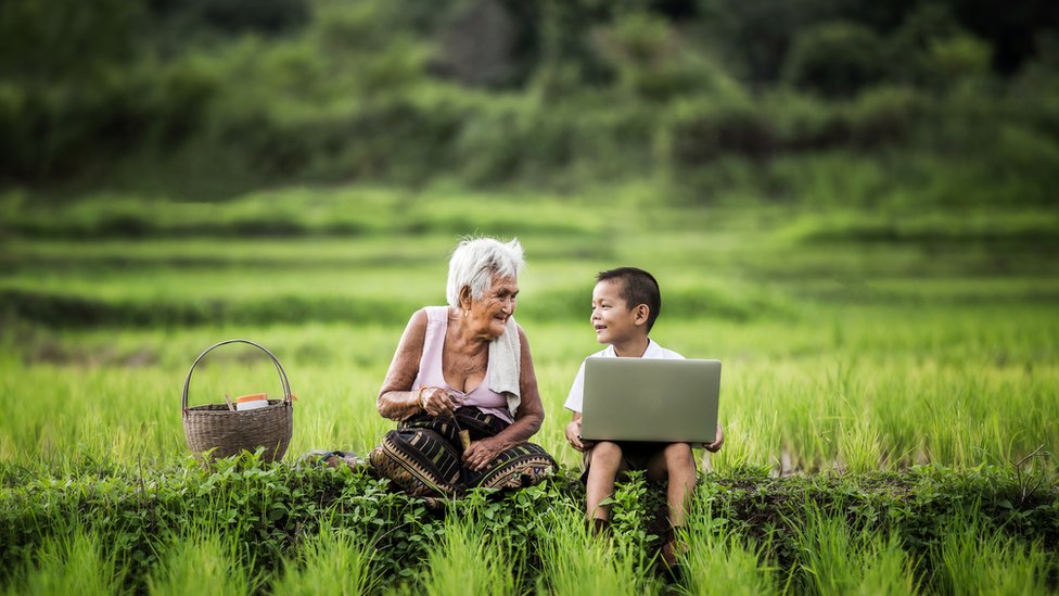 Abuela y niño con computador en el campo.