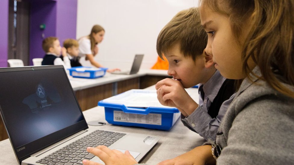 Niños en clase con una computadora.