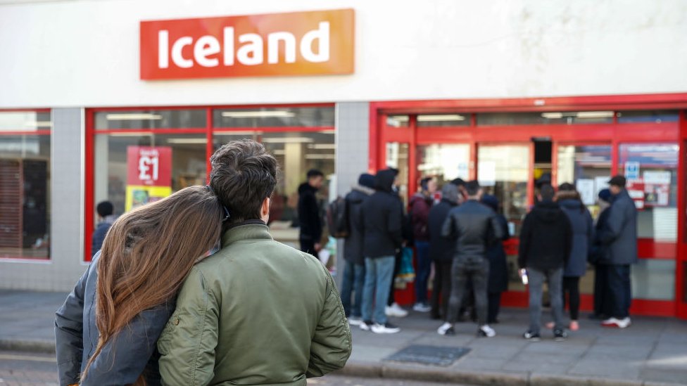 Покупатели смотрят на очередь за пределами Исландии