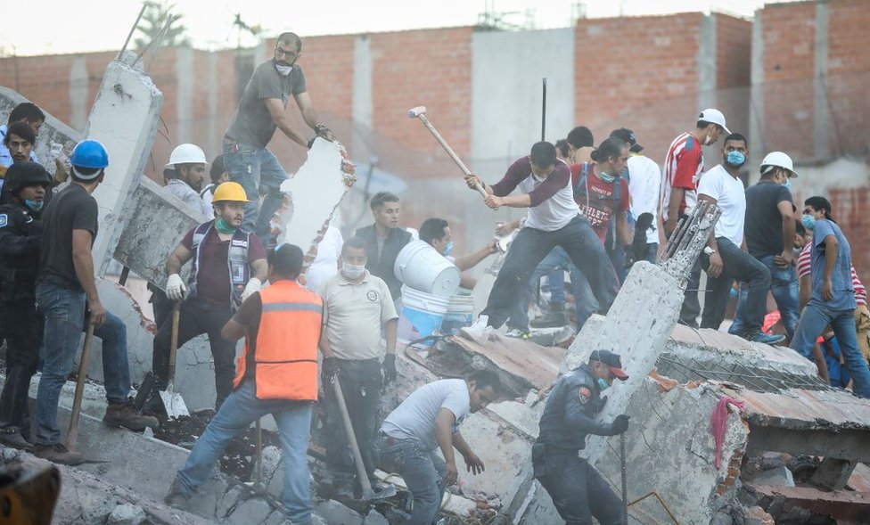 Спасатели с касками и кирками очищают разрушенные здания от завалов