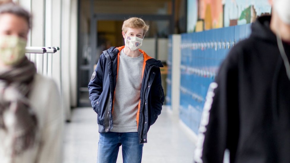 Un joven con mascarilla en una escuela