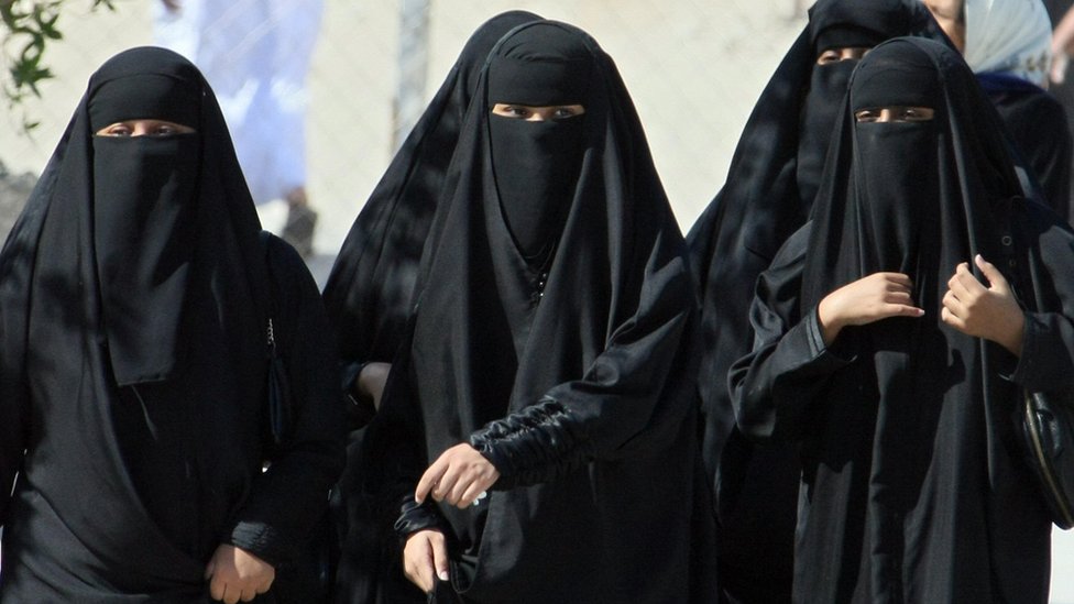 Mujeres sauditas cubiertas con velo caminan en la calle