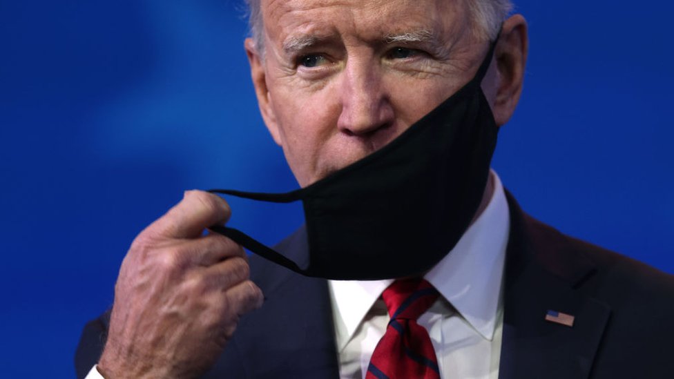 Joe Biden retirando a máscara do rosto
