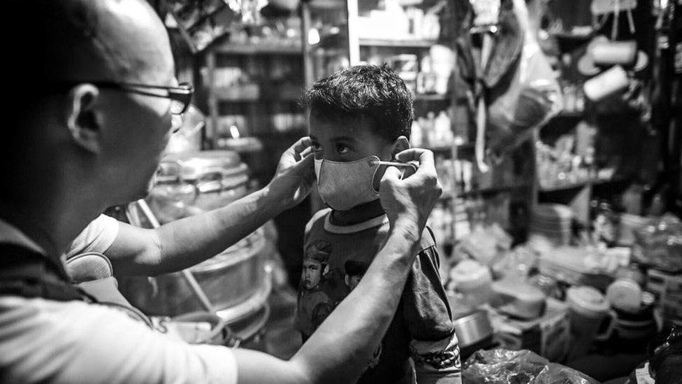 Волонтер помогает ребенку надеть маску N95