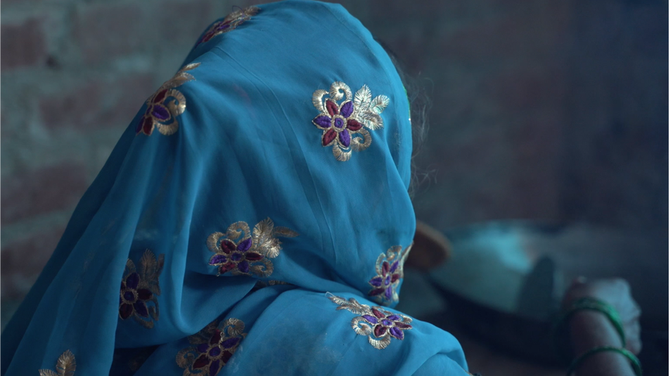 An image of the mother from the back of her head where she`s wearing a blue headscarf