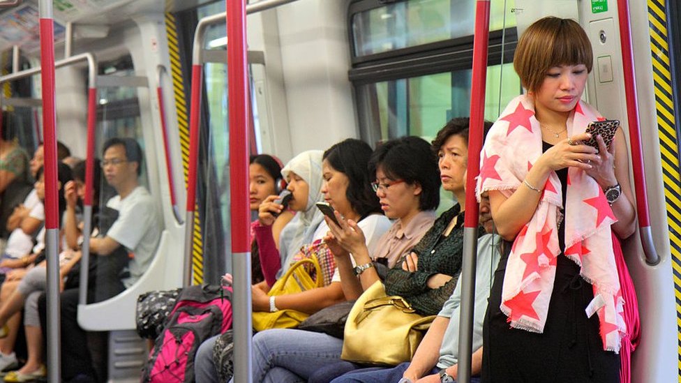 Hong Kong MTR Subway, Airport Express Asian woman checking smartphone.