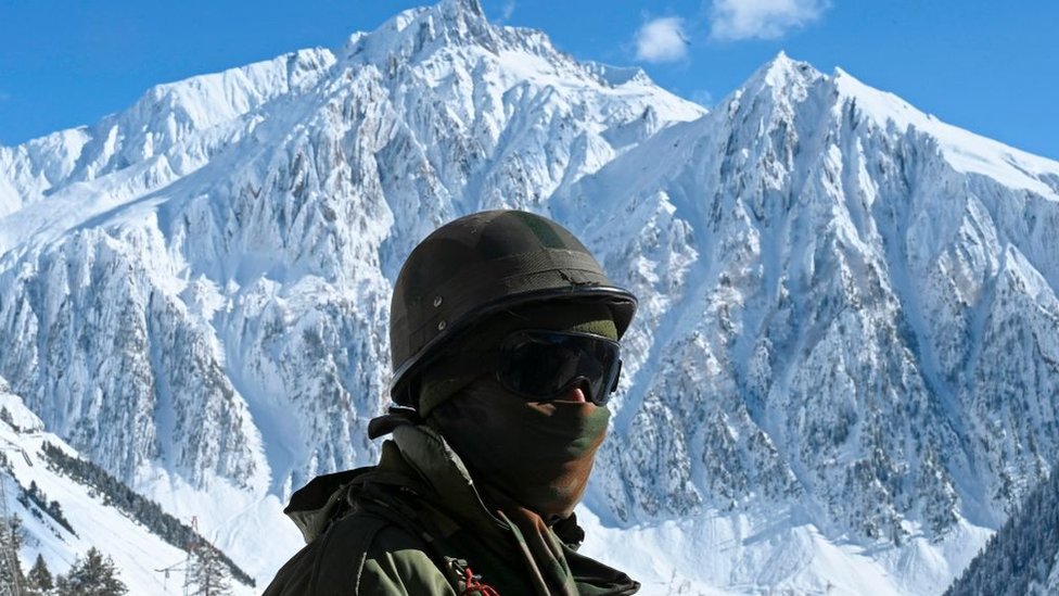 An Indian army soldier stands on a snow covered road that connects Srinagar to the union territory of Ladakh, bordering China