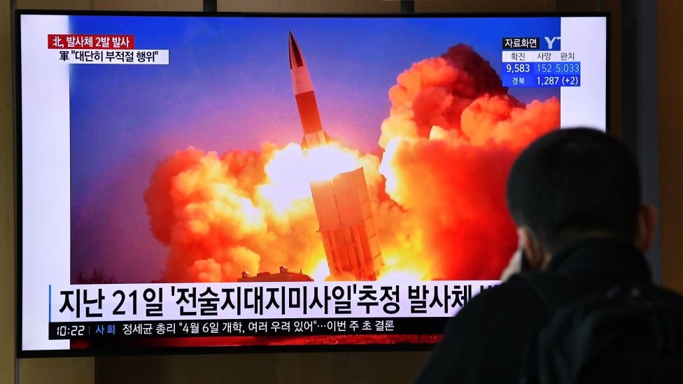 Мужчина смотрит новостную трансляцию, показывающую видеозапись испытания северокорейской ракеты