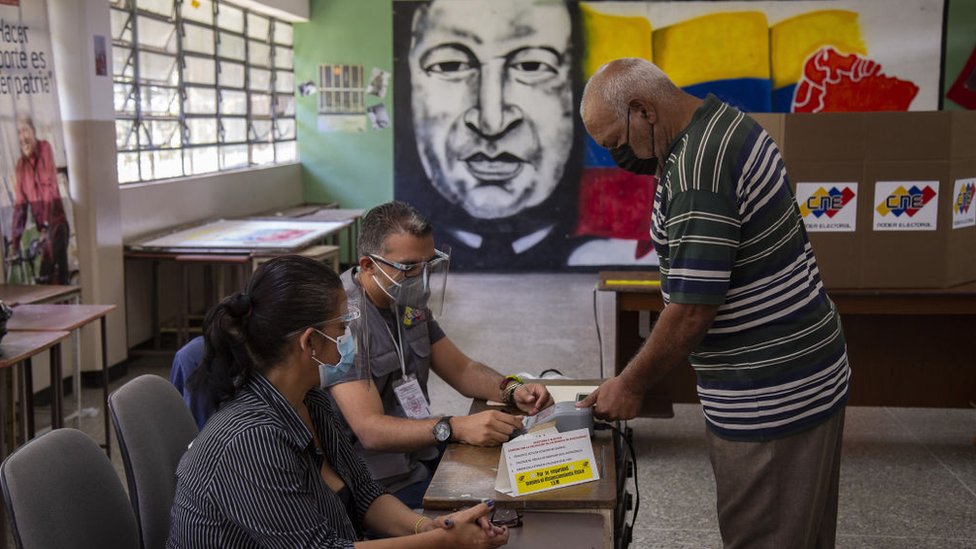 Un votante muestra sus huellas en una máquina en un centro electoral presidido por la imagen de Hugo Chávez.