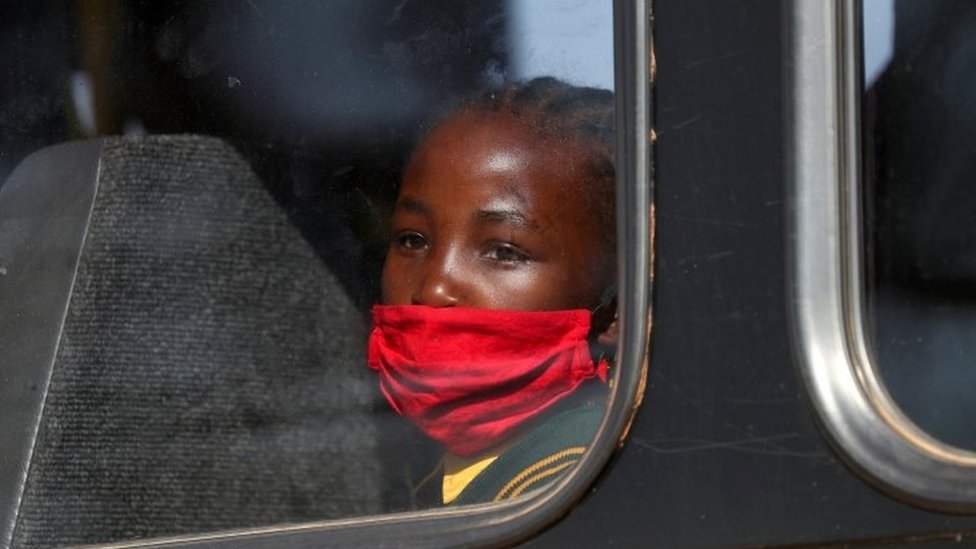 A girl wearing a mask looks out of a bus window in Eikenhof, south of Johannesburg, South Africa.  Photo: August 2020