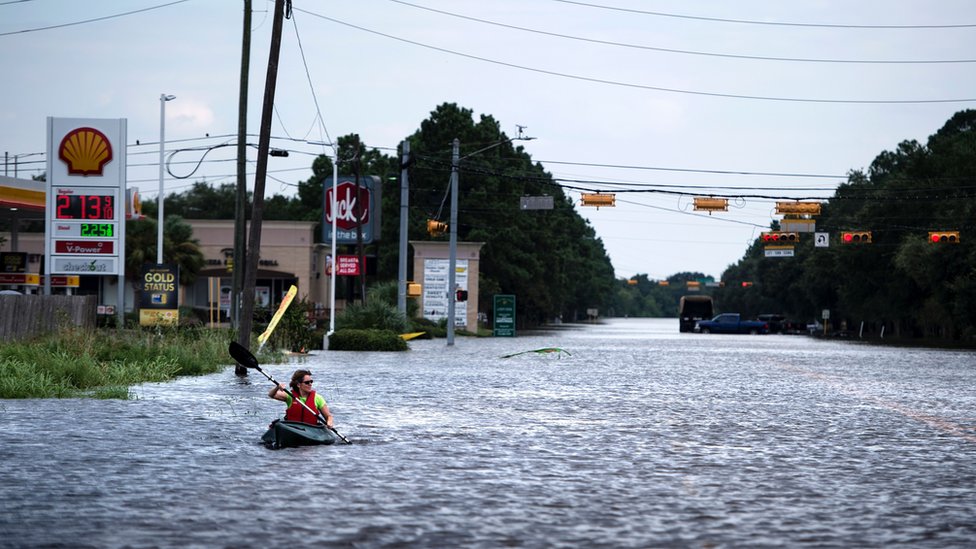 Женщина плывет по затопленной дороге, пока доставляет товар своим соседям после урагана Харви 30 августа 2017 года в Хьюстоне, штат Техас