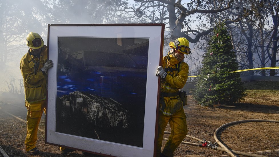 Пожарные снимают картину, продолжая тушить пожары в доме во время «пожара Skirball Fire»