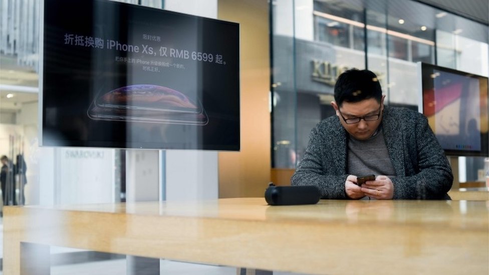 Cliente chino usando un iPhone en una tienda de Apple.