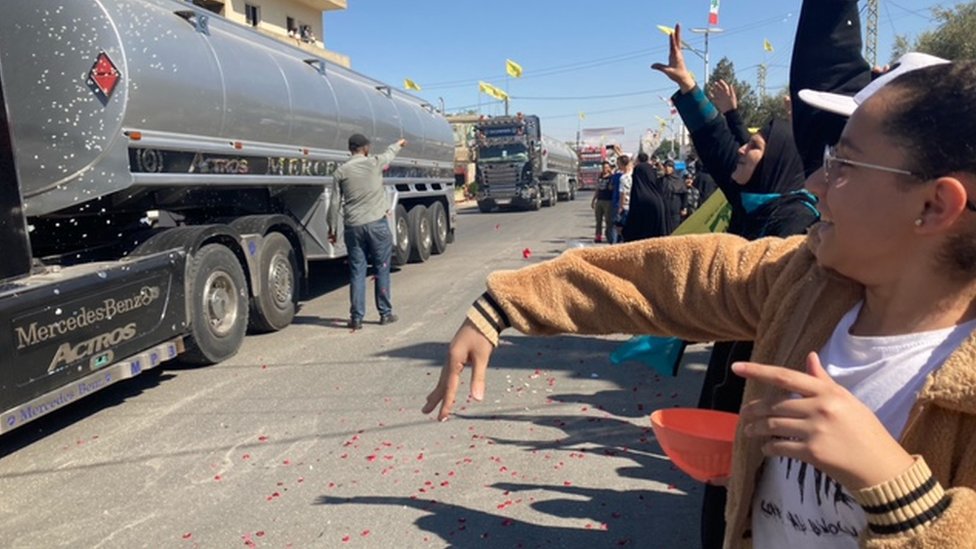Women throw flower petals at lorries brining Iranian fuel from Syria into Lebanon, in the village of al-Ain (16 September 2021)