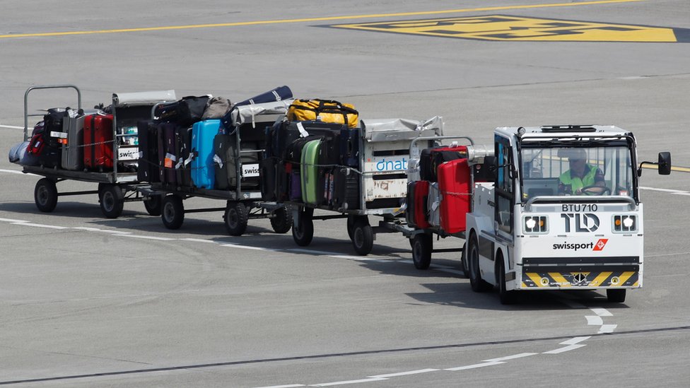 Camión tirando de remolques de equipaje en la pista del aeropuerto