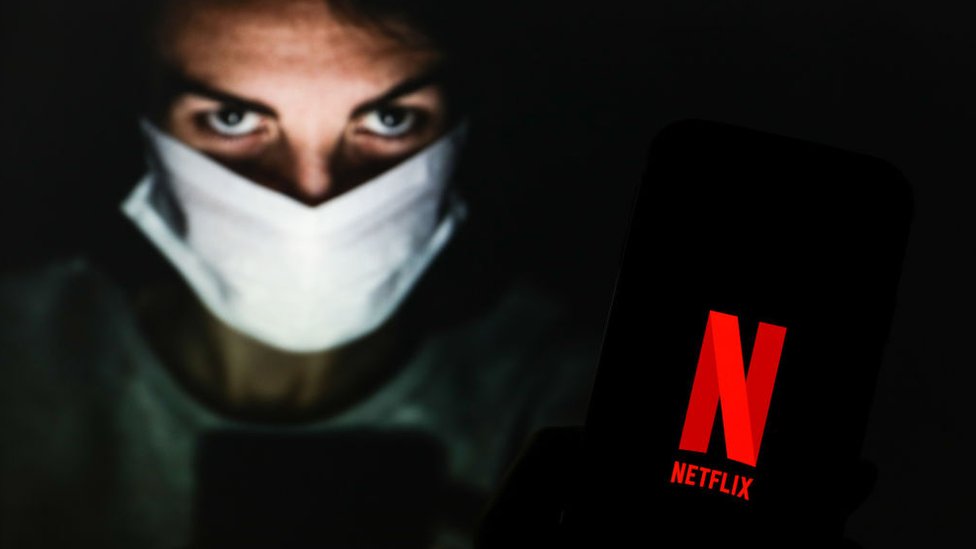 Chico con mascarilla mostrando celular con logo de Netflix