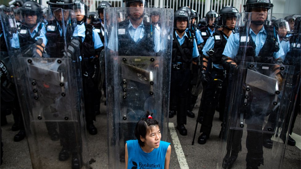 A protester sits in front of riot police outside Legislative Council in Hong Kong