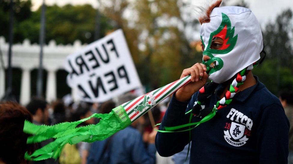 Мальчик в маске наблюдает за демонстрацией в Мехико