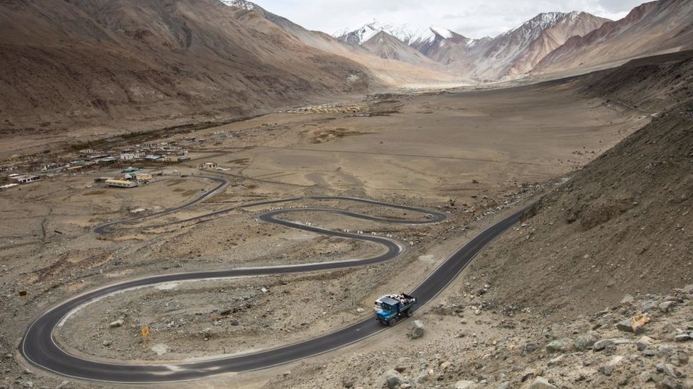 Para pekerja menumpang di belakang truk di sepanjang jalanan Sungai Pangong di wilayah Ladakh.