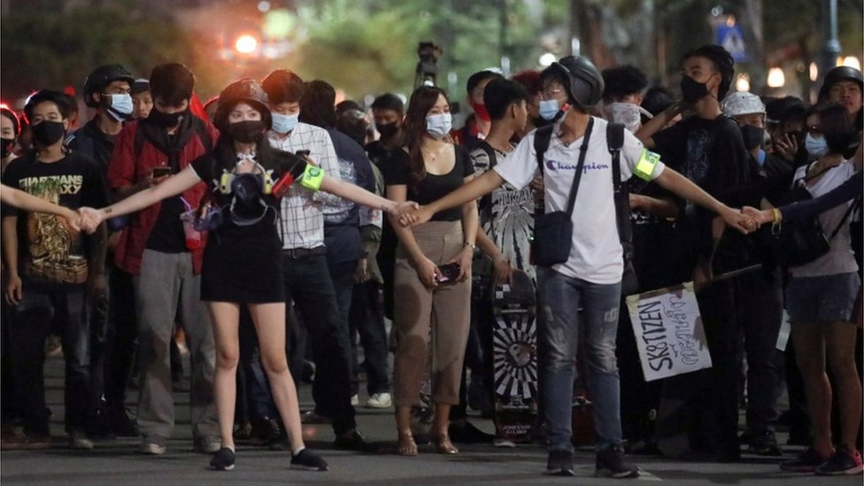 Группа протестующих держится за руки во время марша по Бангкоку