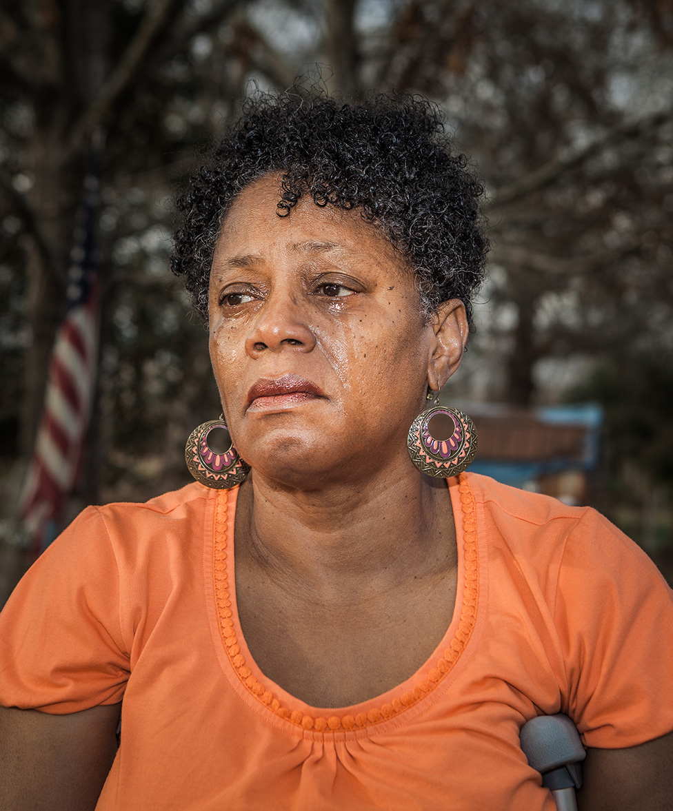 Antoinette Harrell outdoors, with tears running down her face