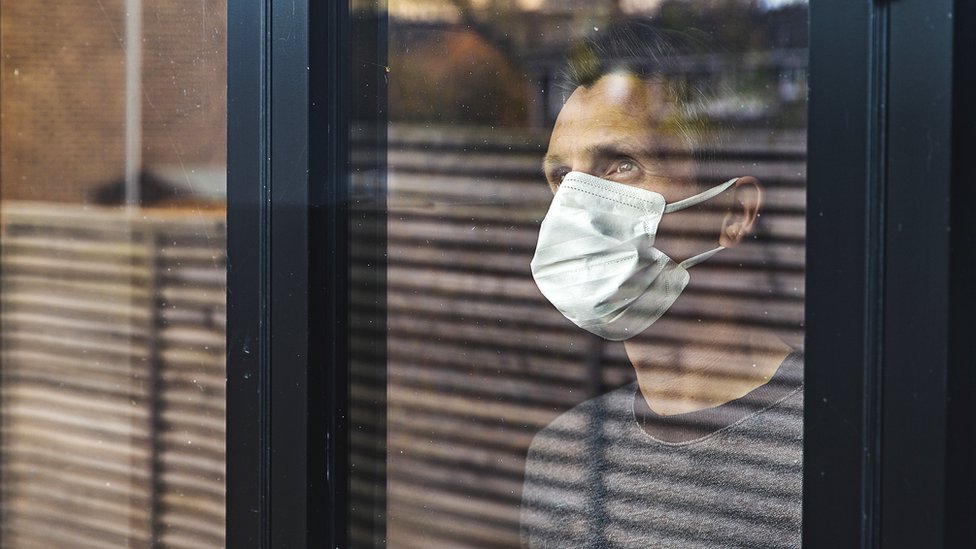 man in mask looking through window