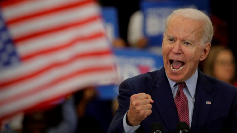 Joe Biden clenching his fist and shouting on stage.