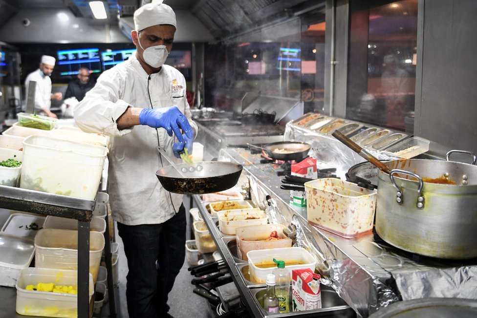 Kitchen staff at the Kebabish Grill restaurant in Glasgow wear masks as they prepare foo