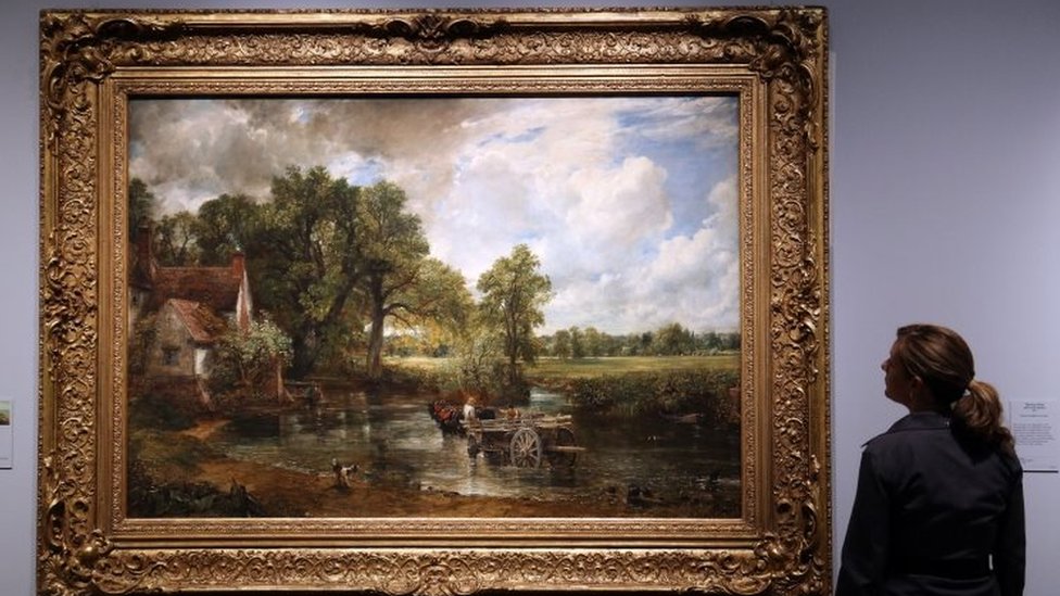 a museum employee looking at John Constable's 1821 painting The Hay Wain