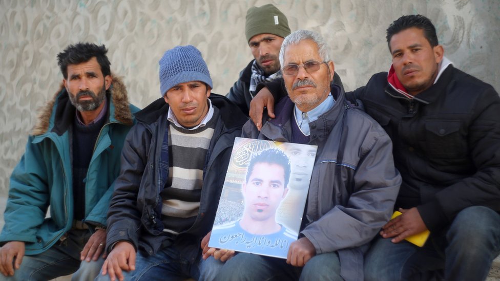 Осман Яхьяуи (С) позирует с членами семьи на фото в центральном тунисском городе Кассерин 21 января 2016 года, держа портрет своего сына Ридхи Яхьяуи