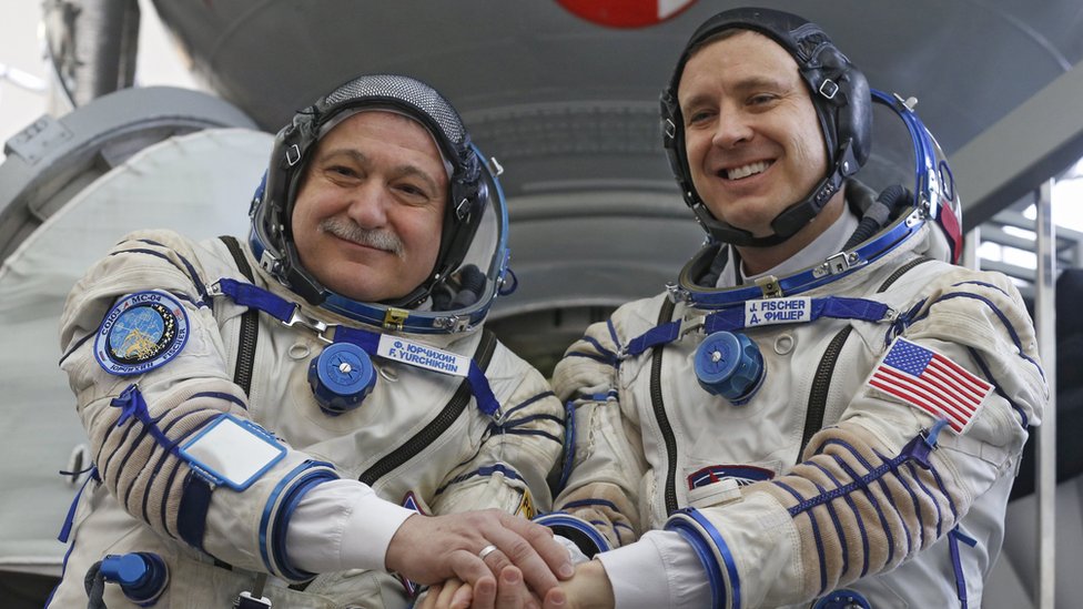 Un astronota y un cosmonauta se saludan