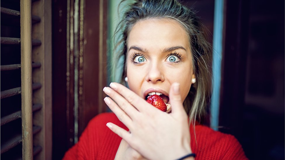 Žena jede jagodu