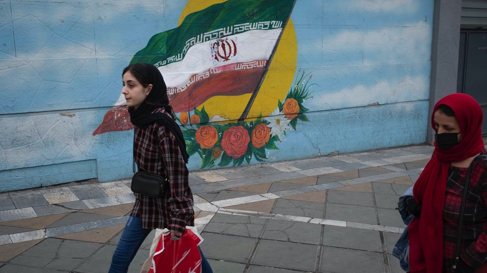 مظاهرات إيران: ما الذي يواجهه المحامون المدافعون عن المحكومين بالإعدام؟ 5 Women walk past an Iran flag in downtown Tehran