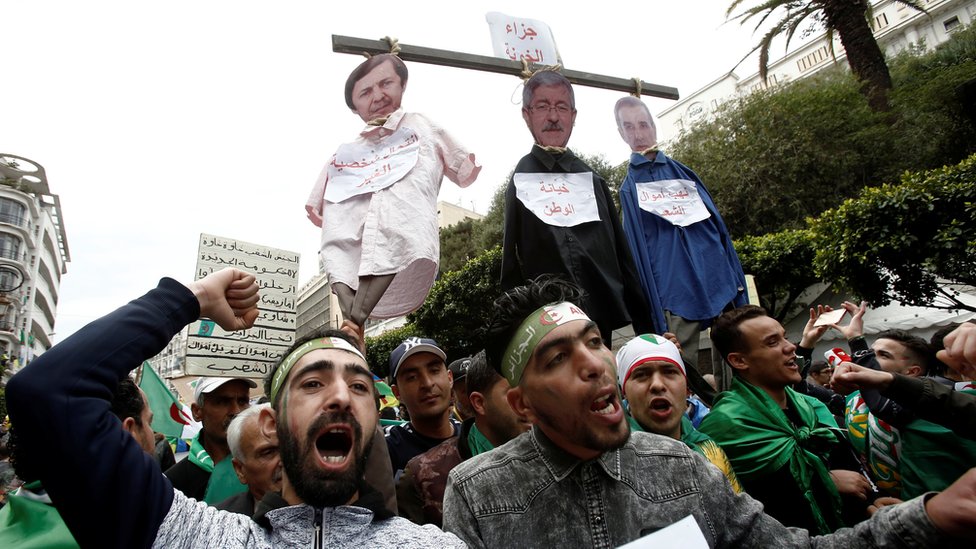متظاهرون يحملون صور لمسؤولين جزائريين في المشنقة