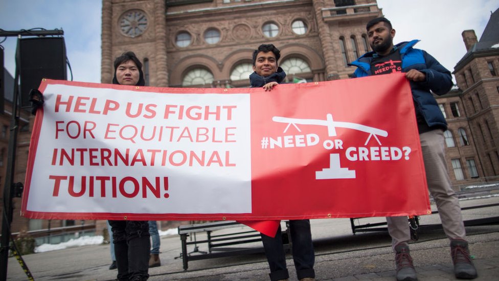 一群在加拿大的國際學生及其支持者手持標語，呼籲人們關注該群體面臨的幾個問題，包括狹窄且昂貴的住房、高昂的學費、僱主的剝削以及獲得永久居留權的艱難途徑