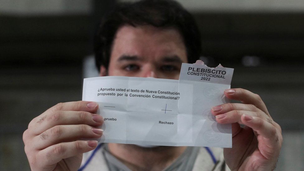 Un hombre sostiene un voto con el rechazo para la nueva Constitución en Chile.