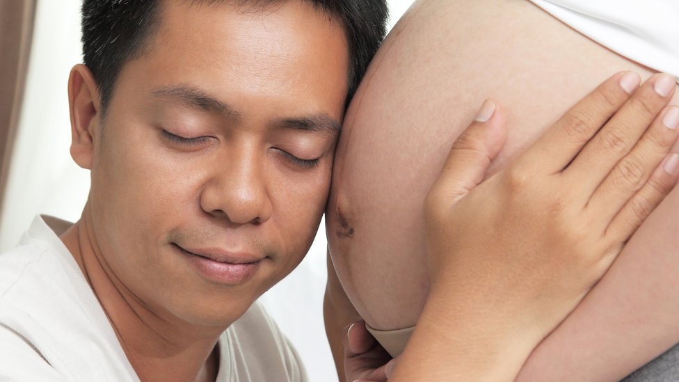 Hombre abraza a una embarazada.