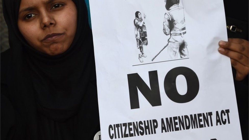 Женщина держит плакат на акции протеста возле университета Джамия Миллия Исламия в Нью-Дели