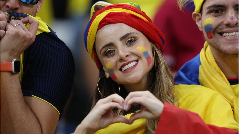 Fanática de Ecuador vestida y pintada con los colores de su bandera forma un corazón con sus manos.