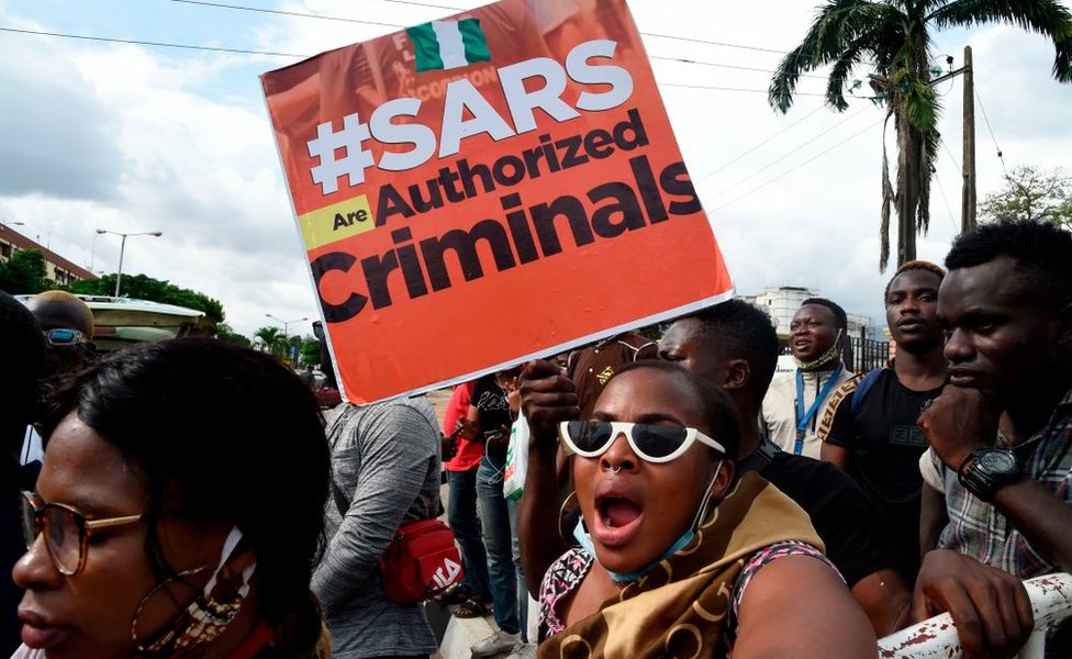 Protesters carry a placard reading "Special Anti-Robbery Squad SARS Are Authorised Criminals"