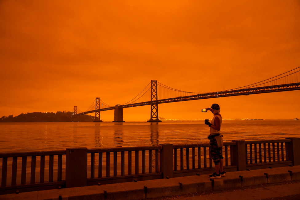 A woman takes in the view from the Embarcadero as smoke from various wildfires blankets San Francisco in darkness and an orange glow on 9 September 2020