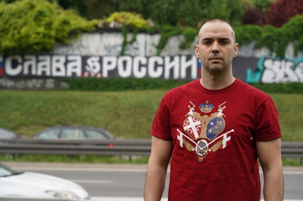 達米揚·克內澤維奇在貝爾格萊德街頭一塊用俄語寫著"榮光歸俄羅斯"的標語前。