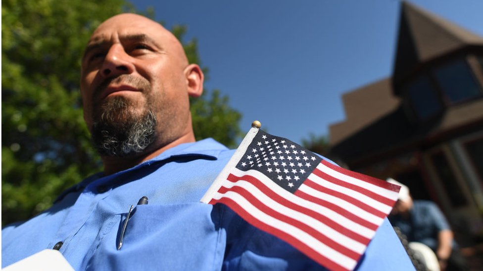 Un hombre con una bandera estadounidense en su bolsillo durante una ceremonia de naturalización