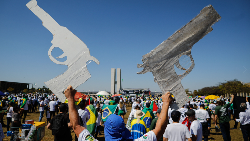 Manifestante segura armas de papel em manifestação diante do Congresso Nacional