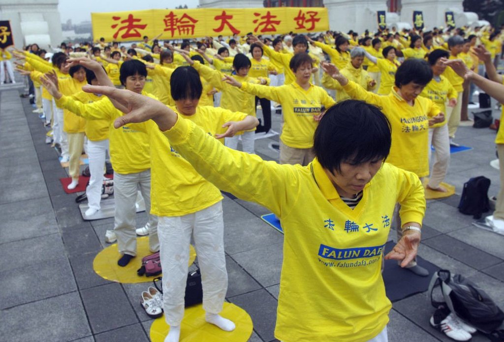 A large group of Falun Gong practitioners make co-ordinated body movements