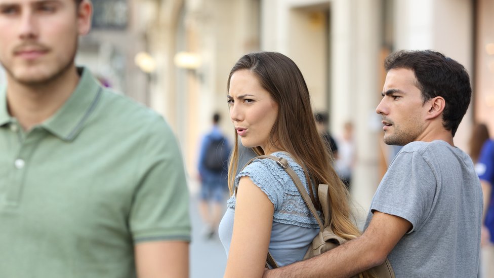 Mujer viendo a otro hombre frente a su pareja.