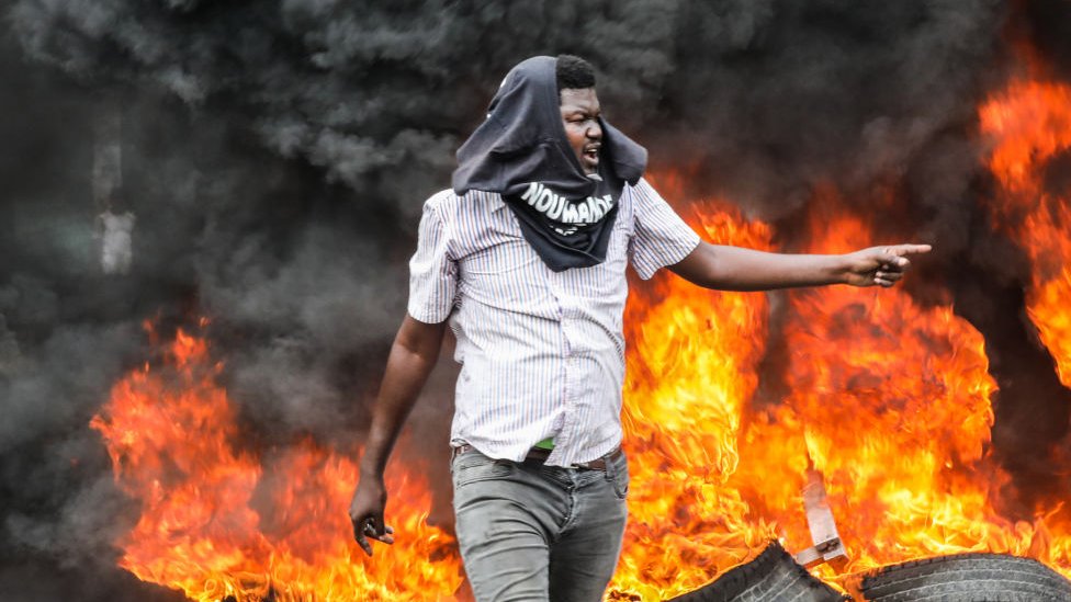 Hombre camina frente a fuego durante unas protestas en Haití