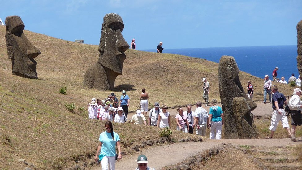 La Isla de Pascua recibe cada vez más turistas y algunos deciden quedarse. Turistas junto a los moáis