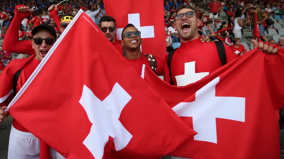 Los suizos también se hacen llamar helvéticos, una referencia a la tribu de los helvecios que estaban asentados en el lugar antes de la conquista de los romanos. Fans con banderas de Suiza